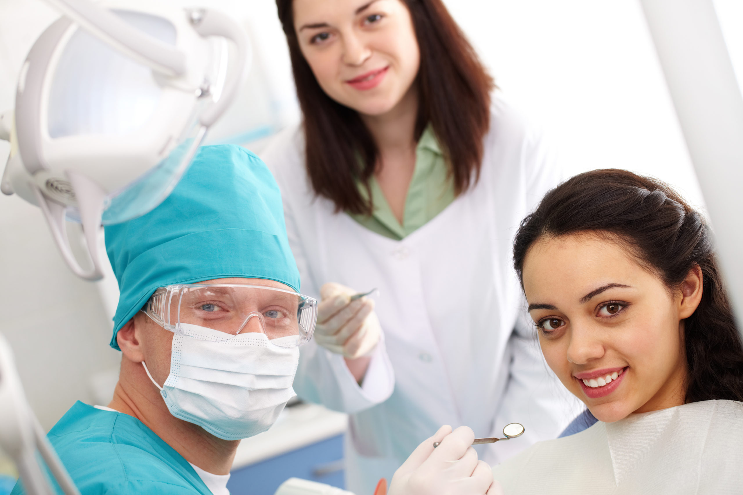 Dentist, his assistant and a patient looking at camera and smiling
