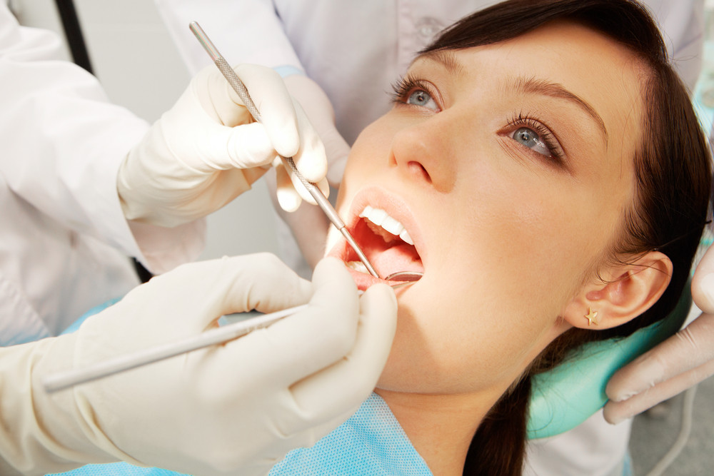 Close-up of a girl examined by two dentists